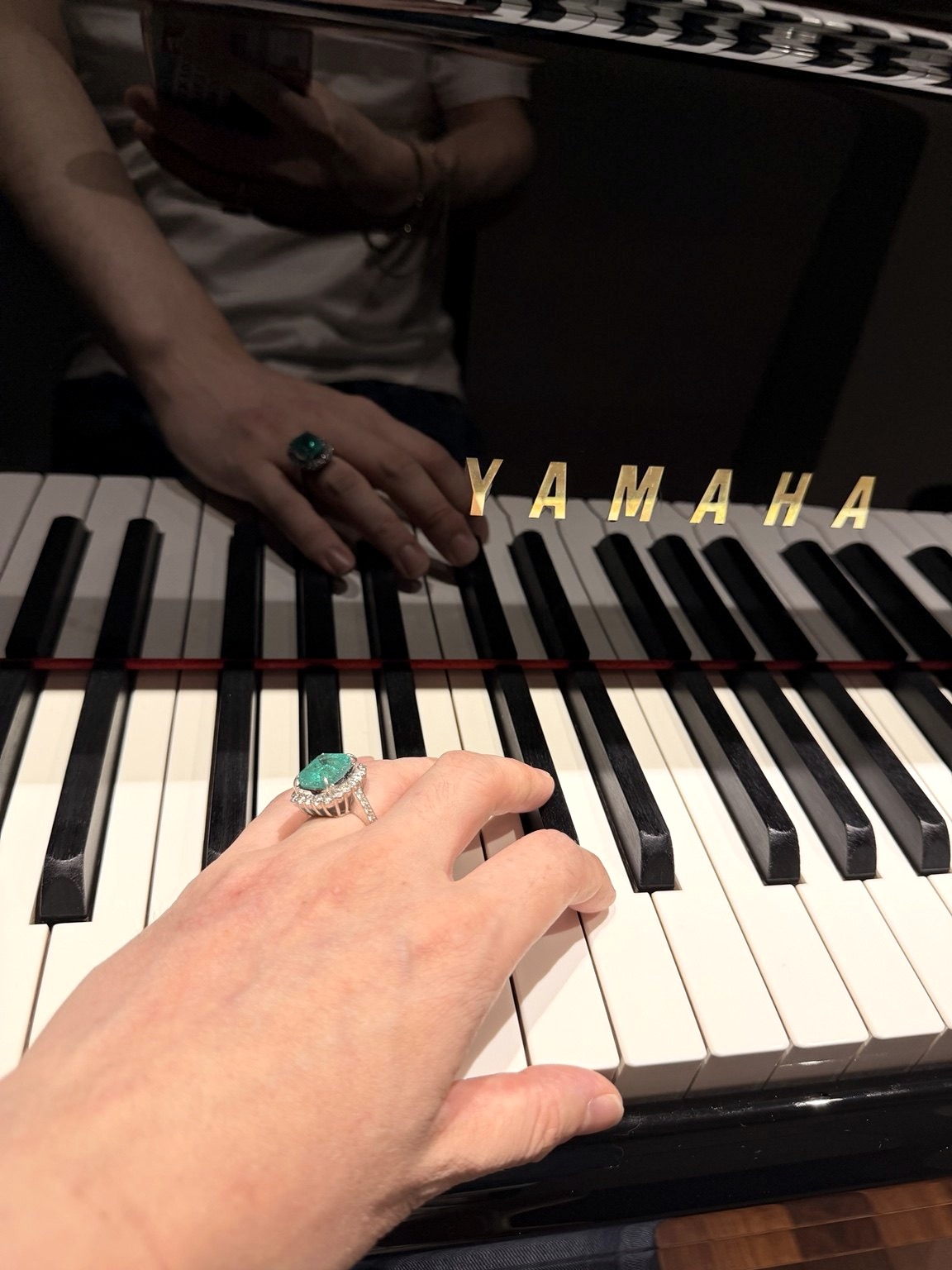 The artist’s hand with a green gemstone ring on piano keys — original personal archive